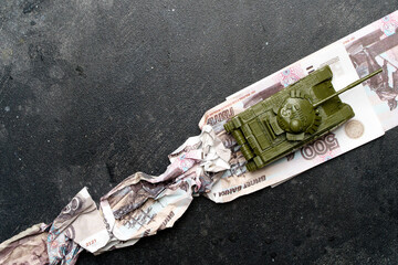 Economic crisis in Russia concept. Toy military tank on Russian rubles. War conflict in Ukraine,...