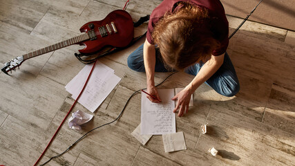 Top view of man writing text of new song on paper - obrazy, fototapety, plakaty