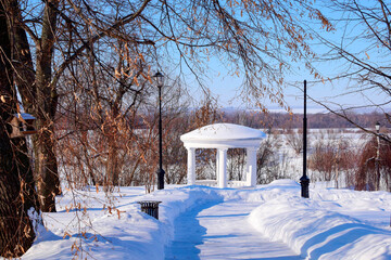 Snow-covered path to the gazebo on the river bank
