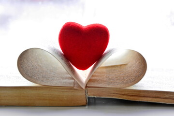 red heart figure as a bookmark for open books between the folded pages on white background