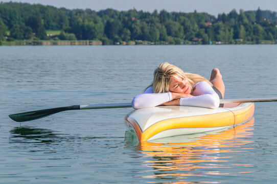 Junge Frau genießt ein entspanntes Sonnenbad auf ihrem SUP-Board