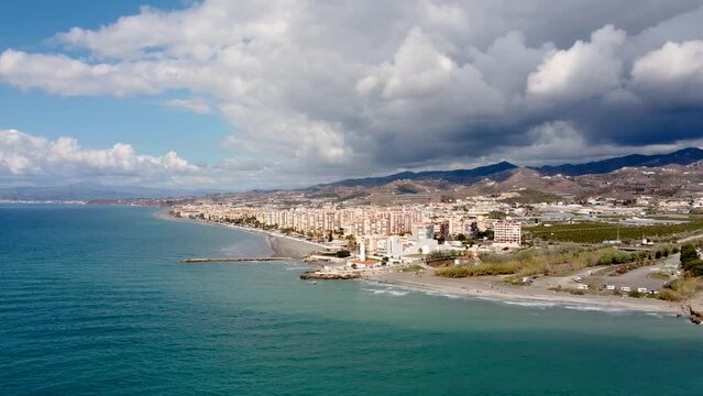 Panoramic aerial view of beautiful costal city Torrox. Drone going forward creating a beautiful  perspective of Torrox Costa. View of the lighthouse of Torrox,  river and promenade of Torrox. 