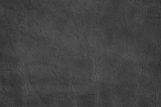 Old cracked black concrete wall texture. Dark aged cement surface. Gloomy grunge abstract background