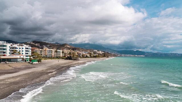 Time-lapse at Pe&ntilde;oncillo Beach in Torrox Costa , Malaga, Spain. Empty beach in winter with cloudy sky and waves. Winter time with few people walking on the beach.  