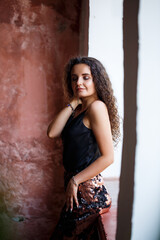 Fototapeta premium Portrait of a young charming woman with curly hair, fair-skinned girl in a black top and with a smile on her face. Curly woman in light clothes