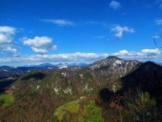 Scenic view of mountain Tosc in the hills of Polhov Gradec, Slovenia and snow covered peaks of...