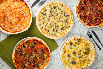 Top view on different freshly baked pizzas on the table
