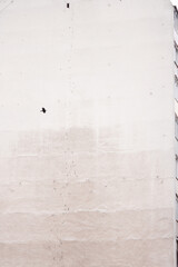 A flying blury bird in the air is against a grey residential building. Black and white shot