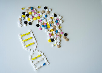 DNA helix made of medicines and colorful pills on wite background next to scattered multi-colored pills