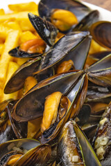 close up of baked mussels with fries on a plate