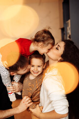 Portrait of overjoyed parents with little kids at home, smiling and cuddling. Happy family with...