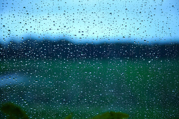 Raindrops on glass and blue sky, grass, forest.
