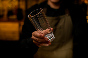 empty tall glass for drink in hand of male bartender