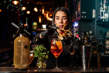 The young Latin brunette prepares a cocktail at the bar counter. job waitress profession