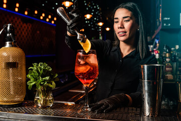 The young Latin brunette prepares a cocktail at the bar counter. job waitress profession