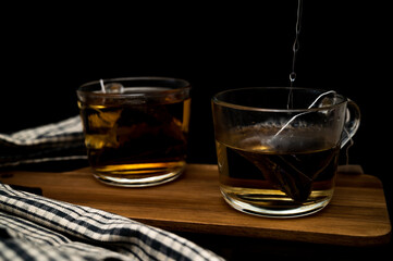 Healthy tea poured into transparent cup. Teapot, lemon, ginger, cardamom, heather bunch and glass jar