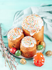 Traditional Russian Ukrainian Easter Cake Kulich. Orthodox Christian Easter Bread or Easter Cake with frosting, Easter Eggs and willow twigs on blue background. Copy space for text, vertical