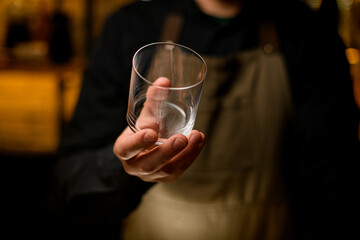 close-up of empty glass for drink in hand of male bartender