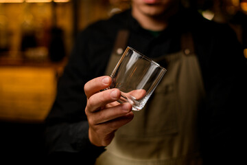 close-up view of empty glass for drink in hand of male bartender