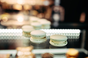 Macaroons close-up, on a glass stand. green tint lined up in pink focus.
Dessert.
