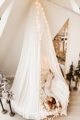 Gorgeous woman lay in canopy bed, smiling, relaxing, adorable lady enjoy weekends, spend winter holidays at home, New Year celebration, Christmas morning concept