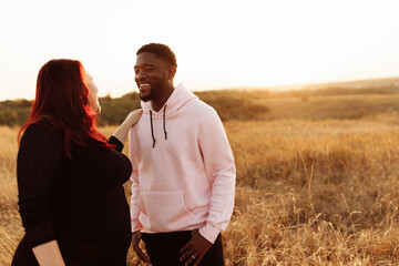Handsome African American man gently hug beautiful white woman at sunset at the field, adorable lady smiling, enjoy tender moments, weekends outdoors, mixed race couple concept
