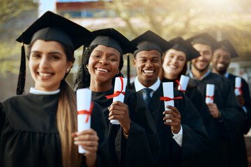 Our future is secure. Portrait of a group of young students holding their diplomas on graduation day.