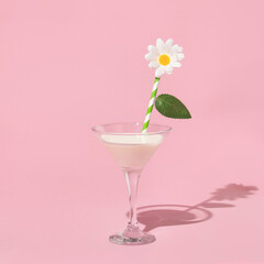 Spring creative pattern with martini glass of milk, drinking straw, flower and leaf on pastel pink background. 80s or 90s retro fashion aesthetic  flowers concept. Minimal romantic surreal idea.