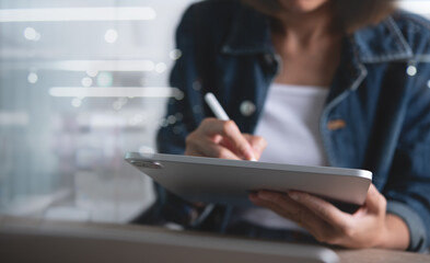 Close up of casual business woman hand working with stylus pen on digital tablet pc.