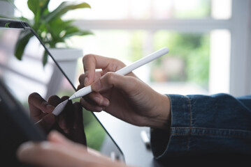 Close up of woman hand with stylus pen touching on digital tablet screen. Female graphic designer...