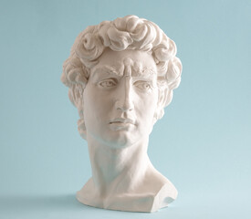 White plaster statue head of David on pastel blue background. Minimal art poster.