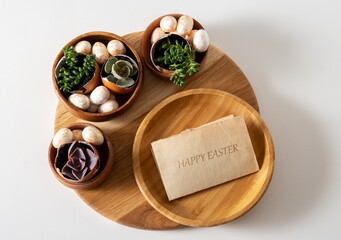 Top view Easter composition with inscription happy Easter and succulent plants in egg shell on white table.