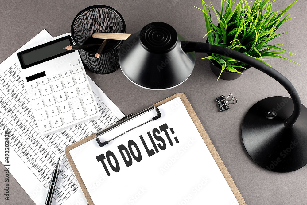 Poster clipboard ,chart and calculator, lamp and workspace accessories on a grey table. top view , text to 