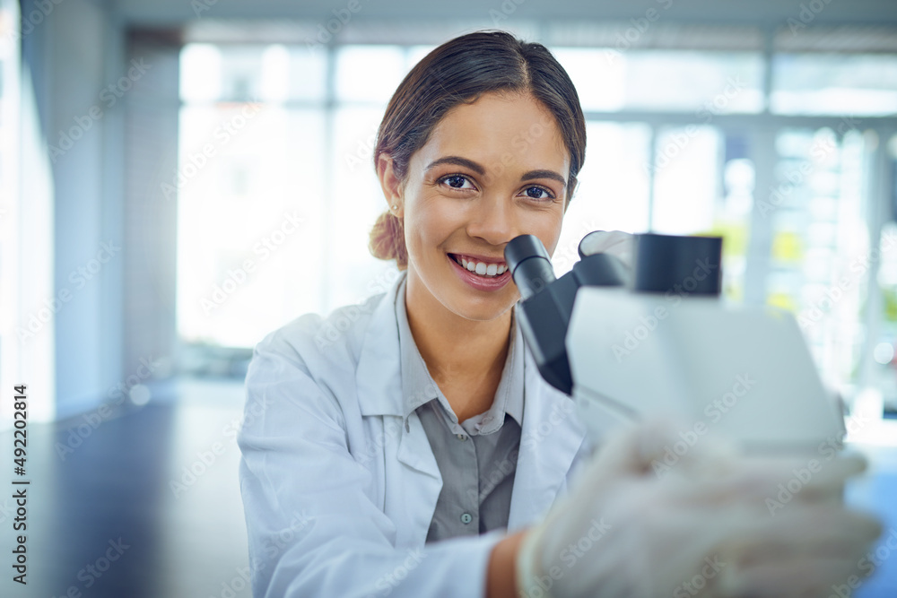 Poster Shes an expert at solving scientific mysteries. Portrait of a young scientist using a microscope in a lab.