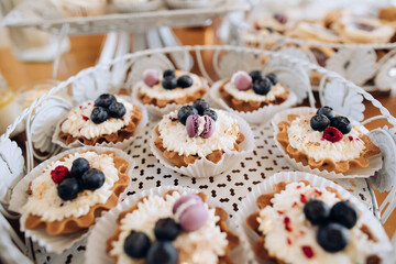 Cakes with cream and blueberries at a wedding party. Table with sweets