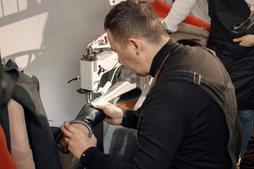 Fototapeta premium Leather craftsman working on a shoe using a special machine