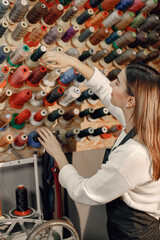 Fototapeta na wymiar Woman tailor choosing colored spools of thread for sewing and embroidery