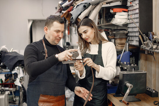 Leather craftsman with master's apprentice working on a belt