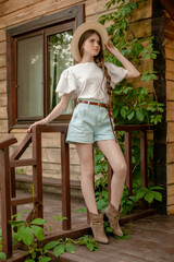 Tween girl posing on wooden threshold of rural house in summer