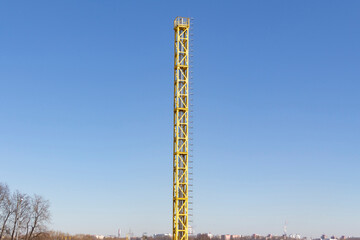 A new, yellow, working boiler room outside on a bright sunny day. Modern fuel and environmental pollution.