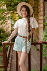 Smiling tween girl standing on wooden threshold of rural house in summer