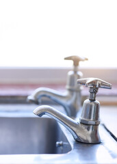 Water is in short supply. Shot of two dripping taps waisting a little bit of water in a basin...