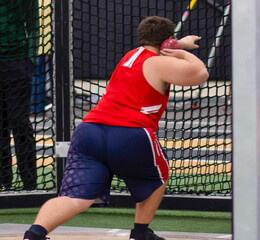 High school athlete in the shot put circle ready to throw a shot put indoor