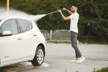Indian man washing his white transportation on car wash