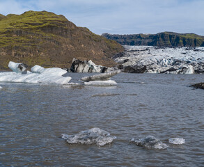 Solheimajokull picturesque glacier in southern Iceland. The tongue of this glacier slides from the volcano Katla. Beautiful glacial lake lagoon with blocks of ice and surrounding mountains.