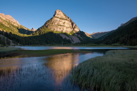 Sunset on La Tour des Sagnes pyramid shaped mountain with Lac des Sagnes in Summer. Ubaye Valley in Mercantour National Park. Alpes de Haute Provence (Alps), France