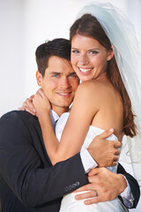 Fototapeta premium Never going to let each other go. Portrait of a couple of young newlyweds embracing warmly and smiling at the camera.