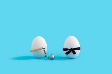 Easter concept with white eggs, one wearing black karate belt and one having medieval mace