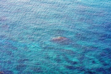 外海府の透明度の高い海にある岩を中心にできた波の輪のような波紋
