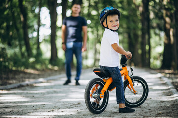 Naklejka premium Father teaching his little son to ride a bicycle